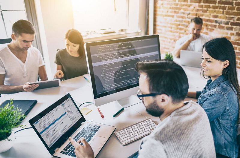 istock.com/scyther5 Mitarbeiter in Meetingraum vor Bildschirmen